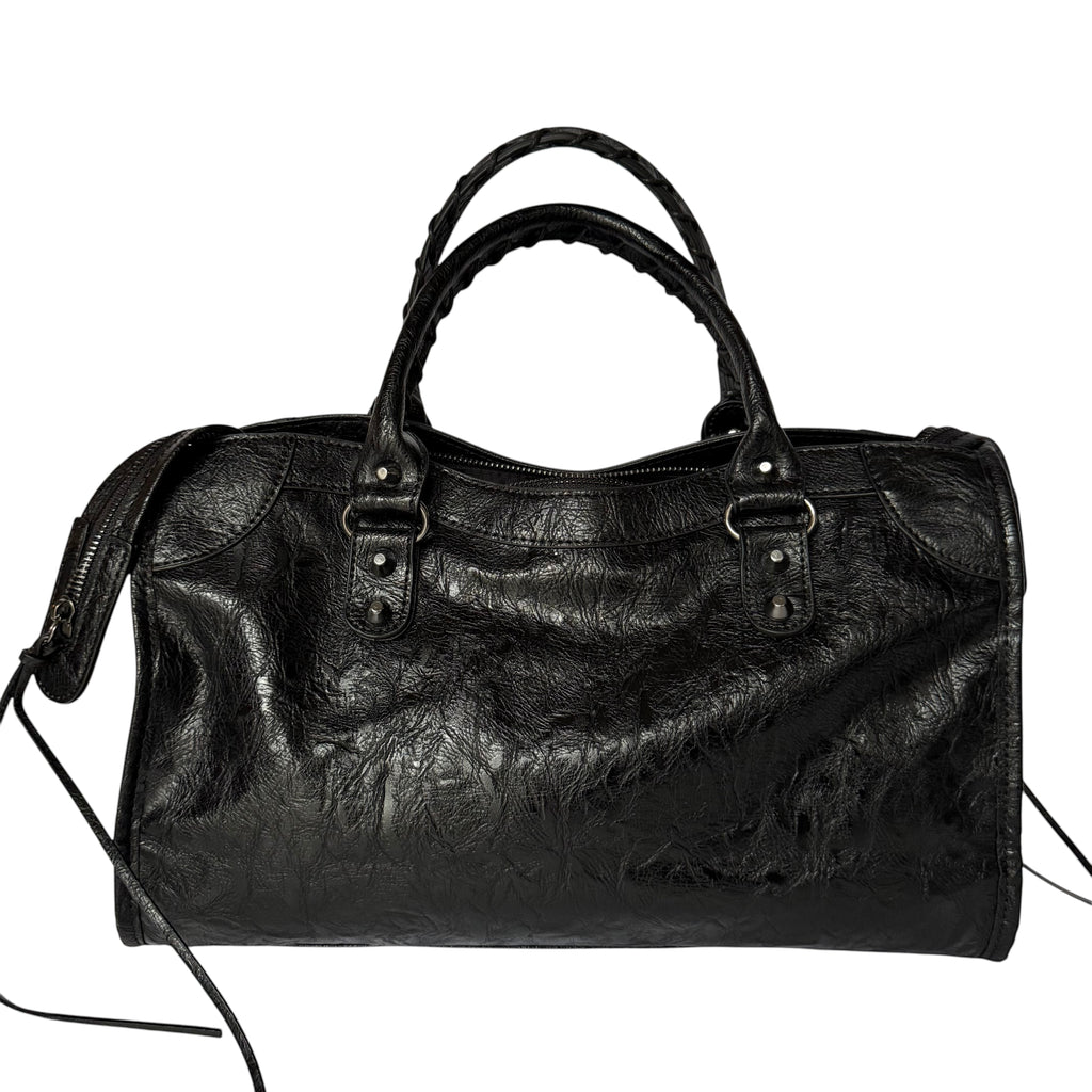 Black vegan leather city bag with braided handles and studded details.