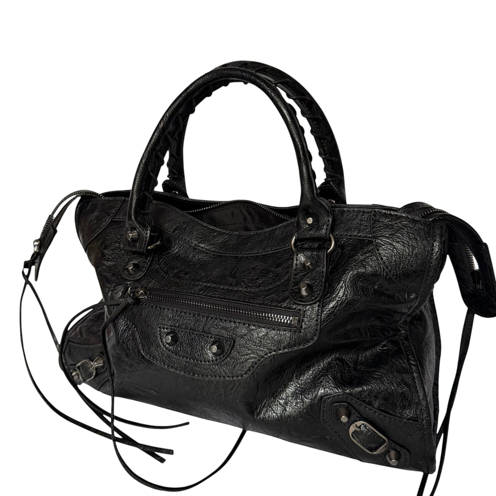 Black vegan leather city bag with braided handles and studded details.