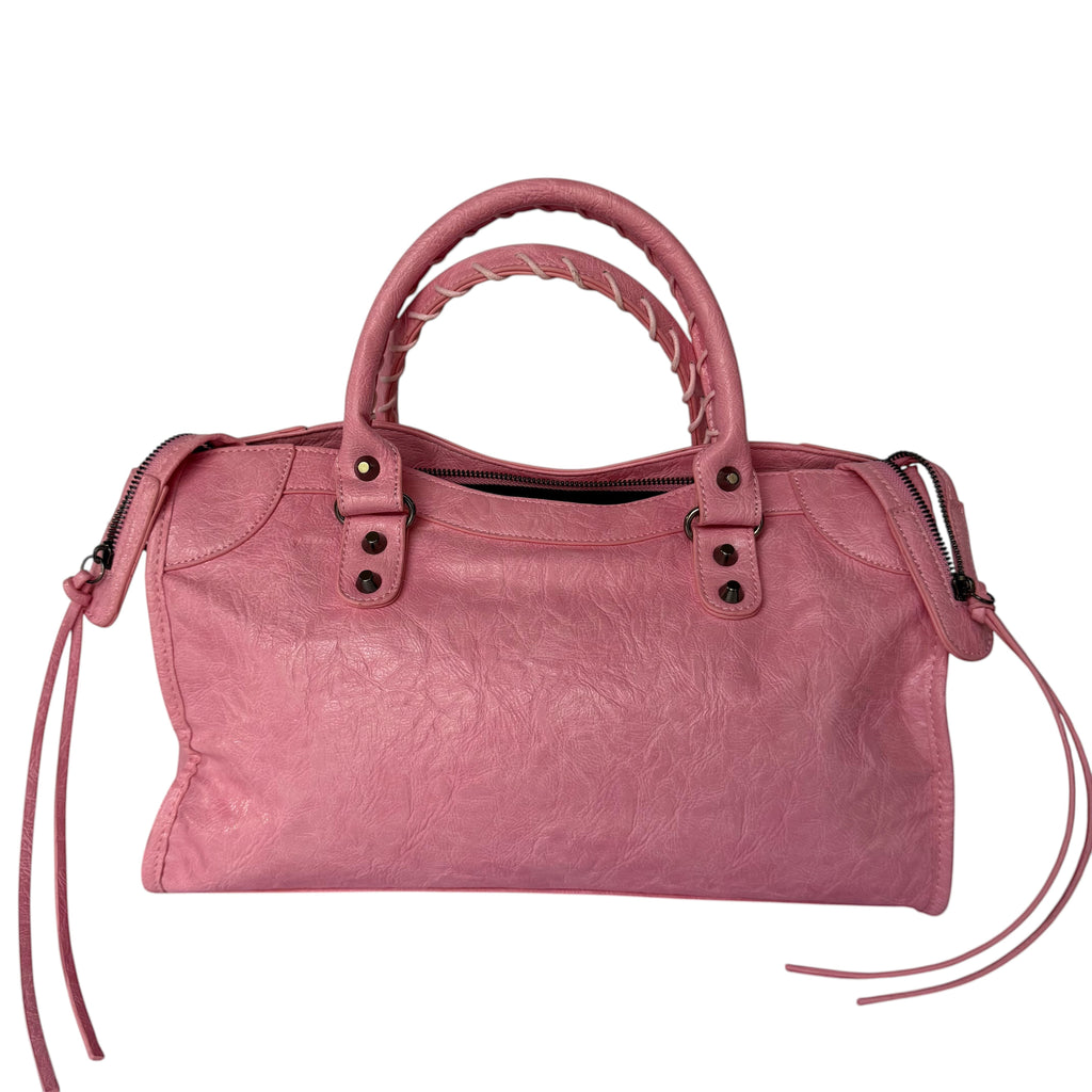 Pink vegan leather city bag with braided handles and studded details.