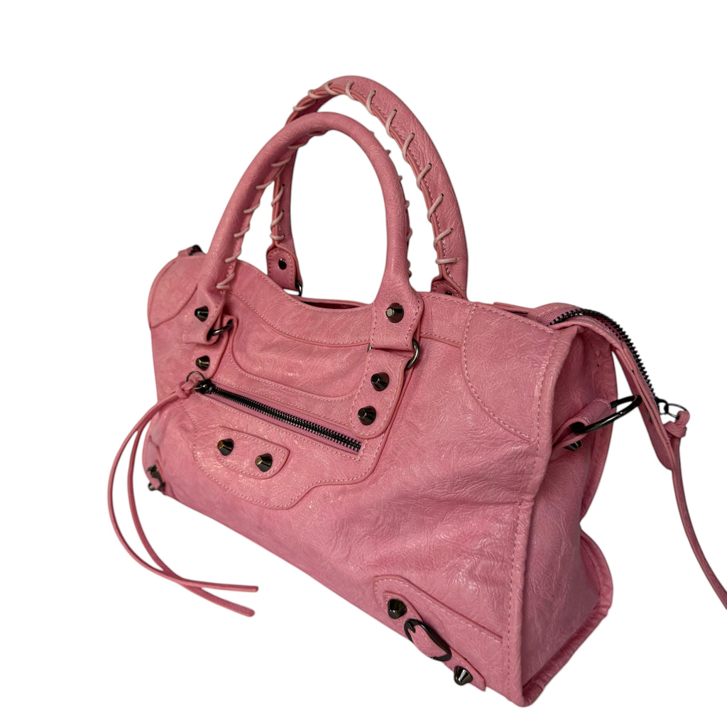 Pink vegan leather city bag with braided handles and studded details.